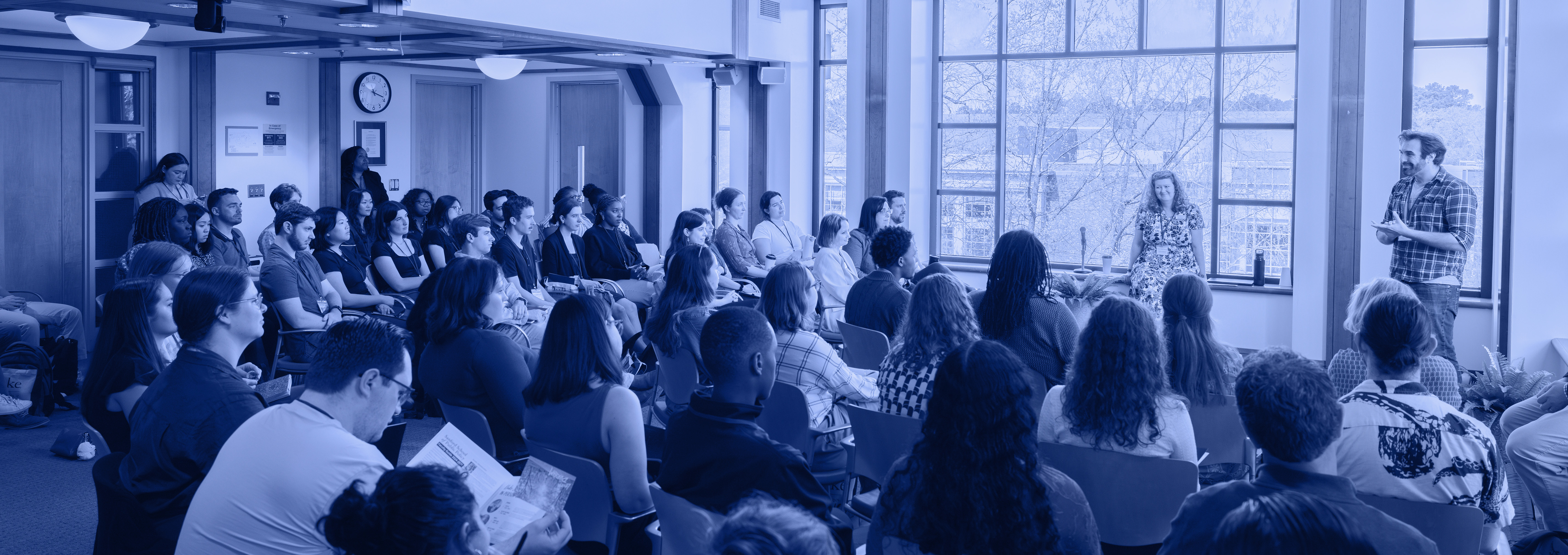 A person speaking in front of a classroom full of students